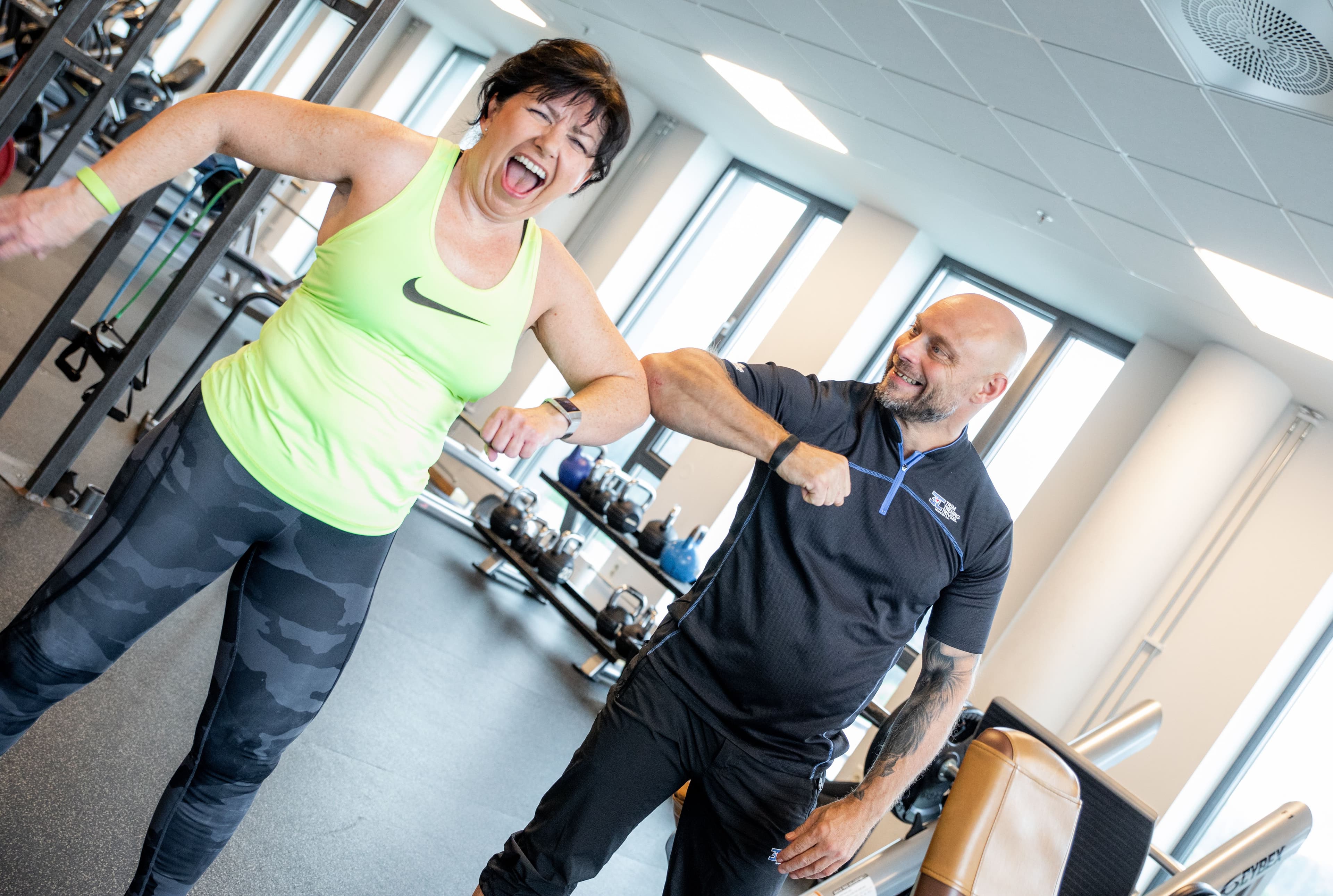 Glad dame som trener med personlig trener på 3T-Treningssenter